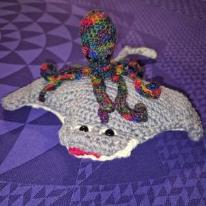Photo of the crocheted rainbow octopus on top of the crocheted manta ray.