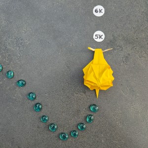 Photo of an origami sea snail leaving a trail of glass pearls