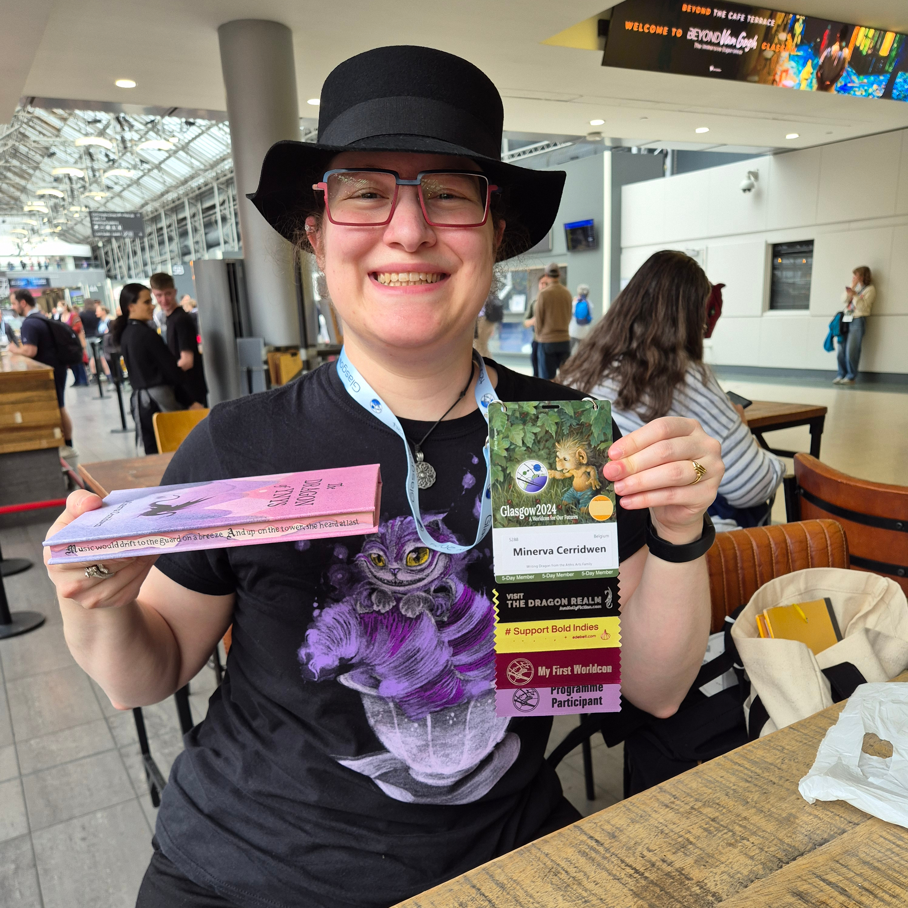 Photo of Minerva showing xyr convention badge and the edge-painted book