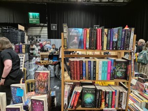Photo of a book rack on a dealers table, with the cover of "Love & Bubbles" on display.
