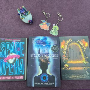 Photo of 3 books, a baby dragon statuette, and two keychains